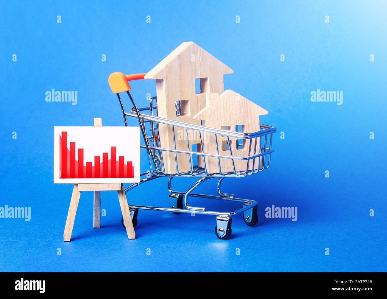 Case di legno in un carrello e un cavalletto con un rosso negativo tendenza grafico. Vendite ridotte. Riduzione dei costi di valore. Scarsa attrattiva. Immobiliare Foto Stock
