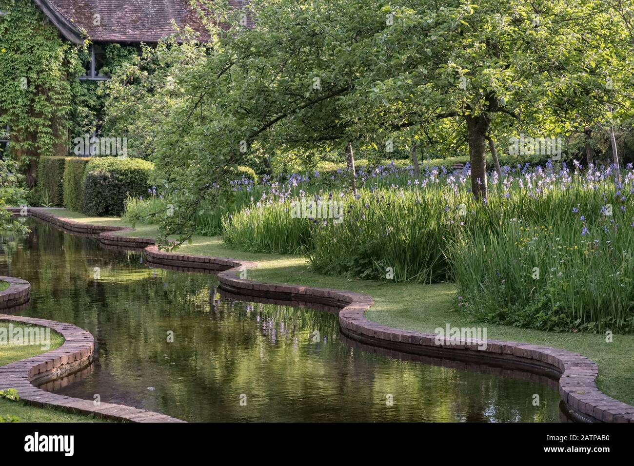 Il canale del giardino Terrestre di Bryan, Herefordshire, Regno Unito, a fine maggio. È fiancheggiata da irici siberiani blu (iris sibirica) Foto Stock