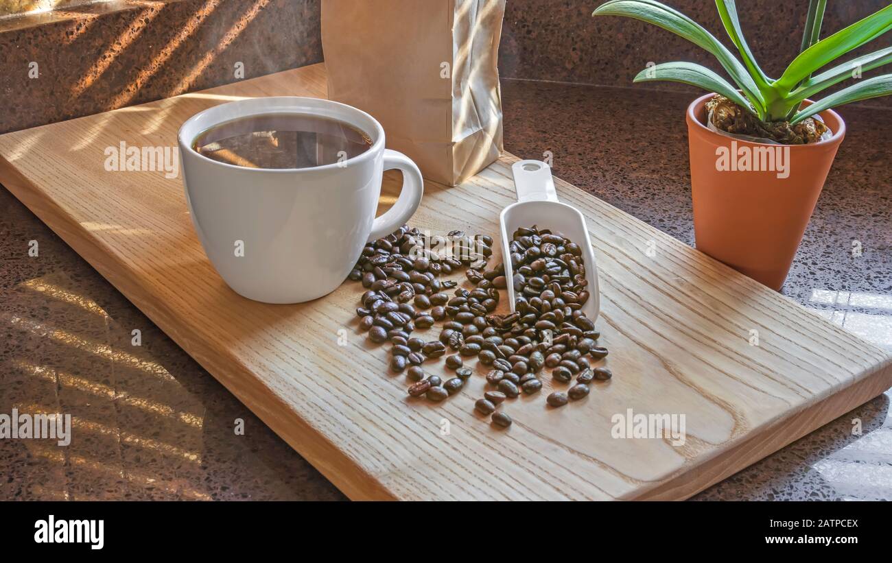 Caffè appena fatto con scoop di chicchi di caffè o tagliere di legno. Ambiente interno cucina. Foto Stock