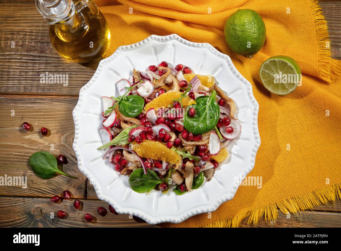 Insalata servita su un piatto di porcellana con fette di arancia, melograno, rucola e funghi di ostriche, su una scrivania di legno e tessuto, cibo, Russia Foto Stock