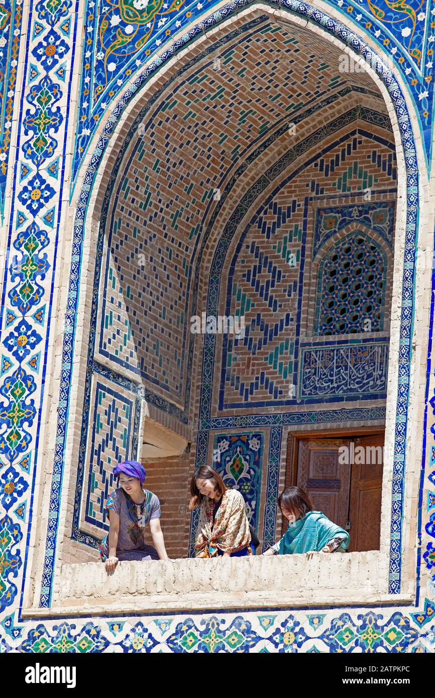 Donne uzbeke in una nicchia ogivale dell'Ulug'Bek Medrese, Piazza Registan, Samarcanda, Provincia Samarqand, Uzbekistan Foto Stock