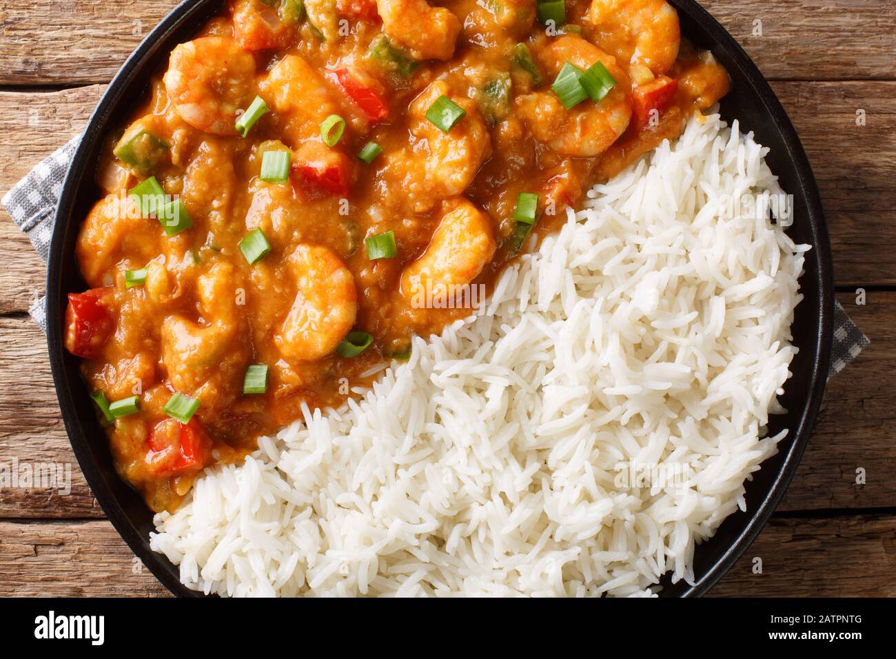 Gamberi Creole Etouffee piatto con sedano, cipolla e pepe cotto in salsa roux servito con riso primo piano in un piatto sul tavolo. Vista dall'alto orizzontale Foto Stock