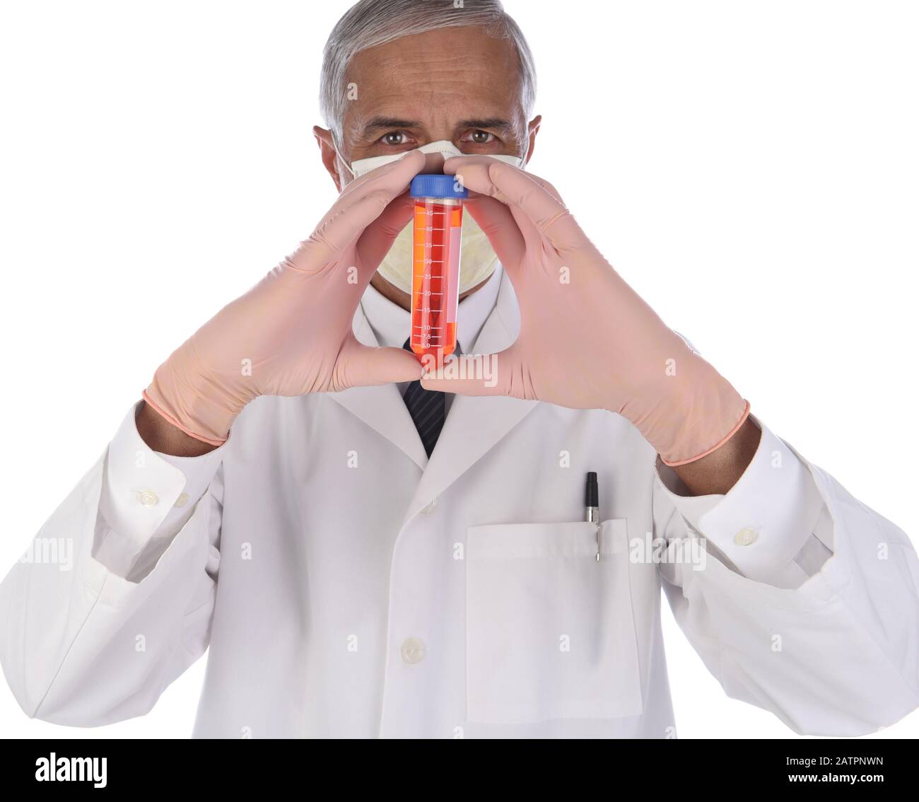 Tecnico di laboratorio che tiene una fiala di liquido rosso in entrambe le mani davanti al viso. L'uomo indossa un camice da laboratorio e una maschera protettiva per prevenire l'infezione Foto Stock