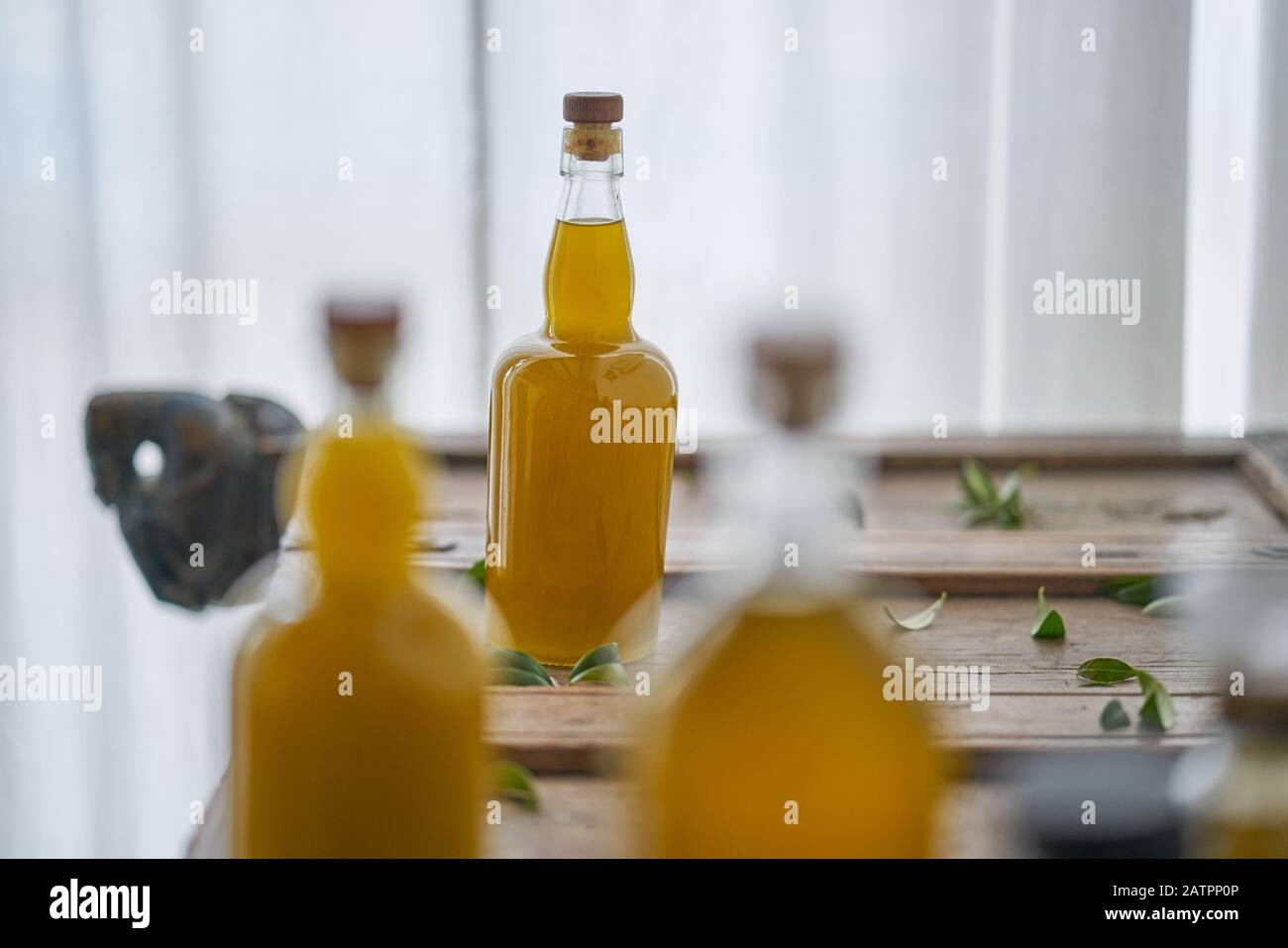 dettaglio di bottiglie riempite di olio liquido dorato succo sano organico fresco corpo benessere su un pezzo di legno mediterraneo di mobili affilati s Foto Stock