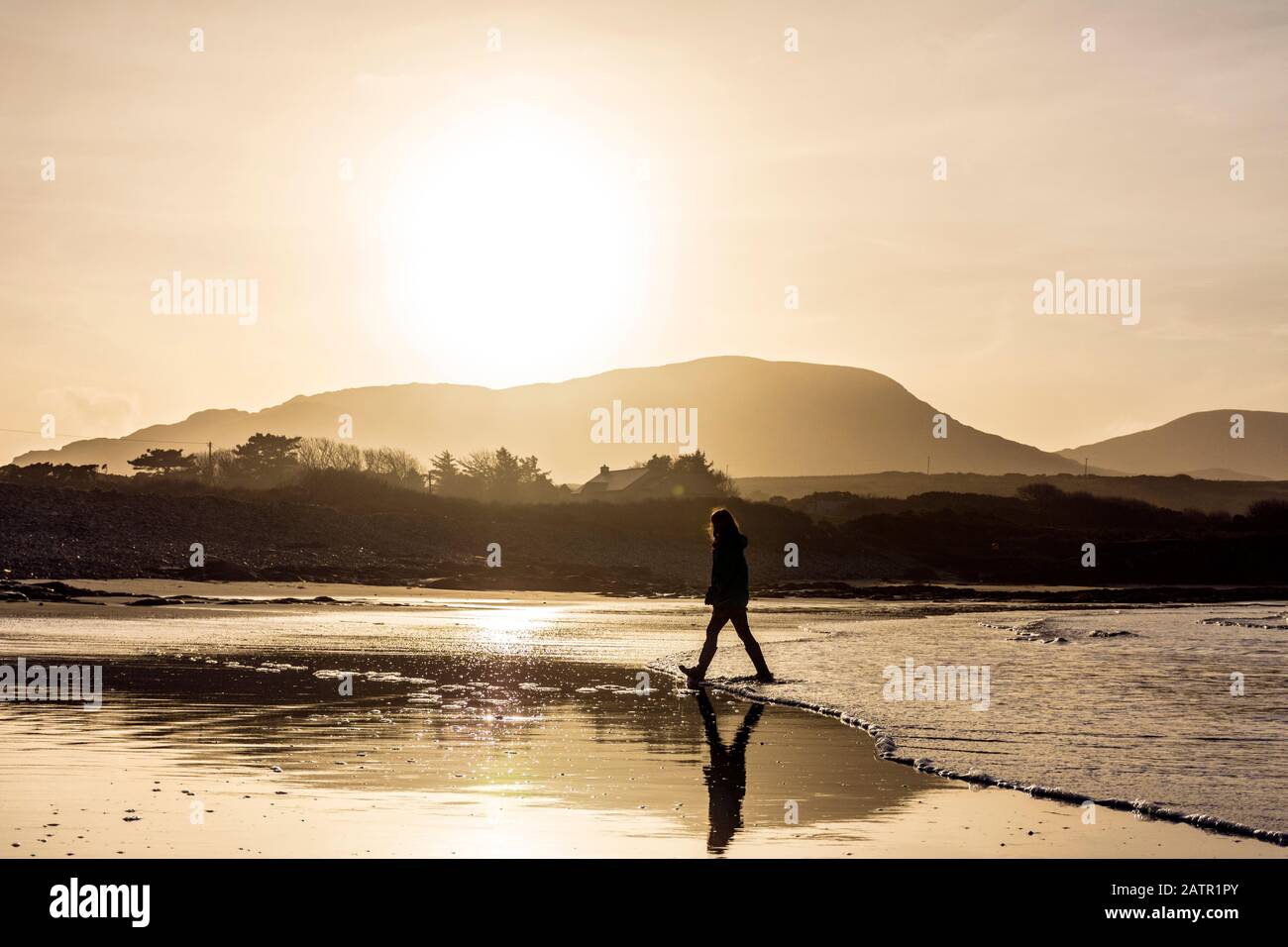 Ardara, Contea di Donegal, Irlanda. 4 febbraio 2020. Il sole invernale basso silhouette un camminatore sulla spiaggia 'Wild Atlantic Way'. Foto Stock