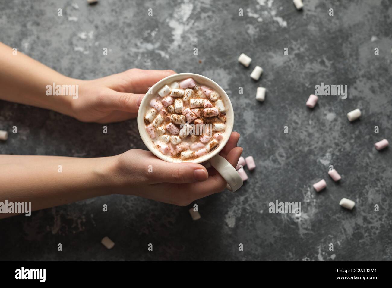 Mani che tengono una tazza bianca di bevanda calda di cacao con marshmallows con spazio della copia Foto Stock