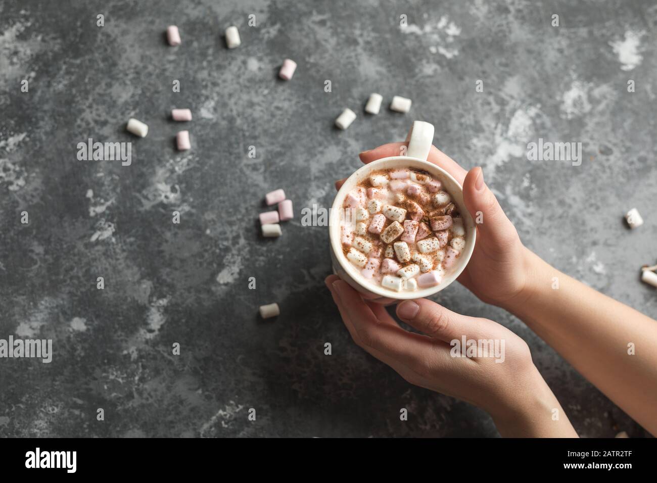 Mani che tengono una tazza bianca di bevanda calda di cacao con marshmallows con spazio della copia Foto Stock