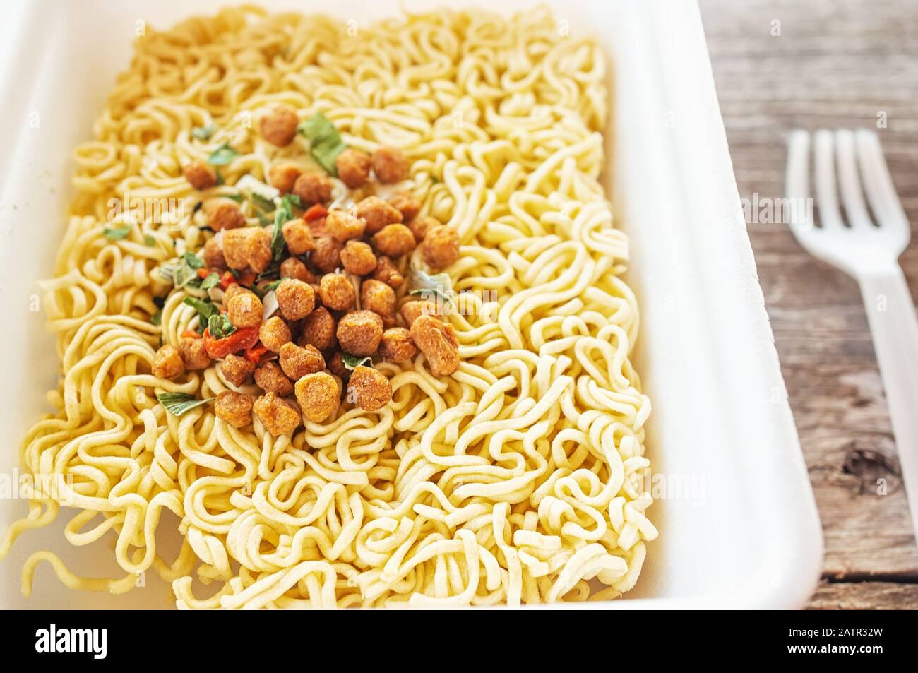 ciotola di minestra di ramen. Tom Yam kun noodles istantaneo con carne secca e additivi vegetali su un tavolo di legno. Zuppa rapida preparata a caldo in una confezione monouso Foto Stock
