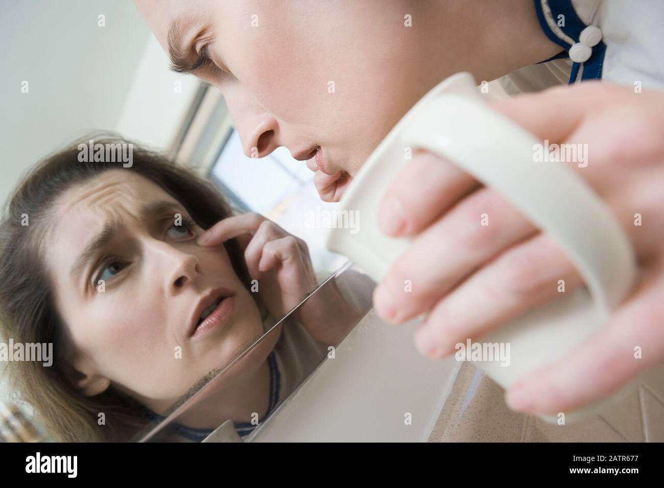 Close-up di una metà donna adulta controllare i suoi occhi in uno specchio Foto Stock