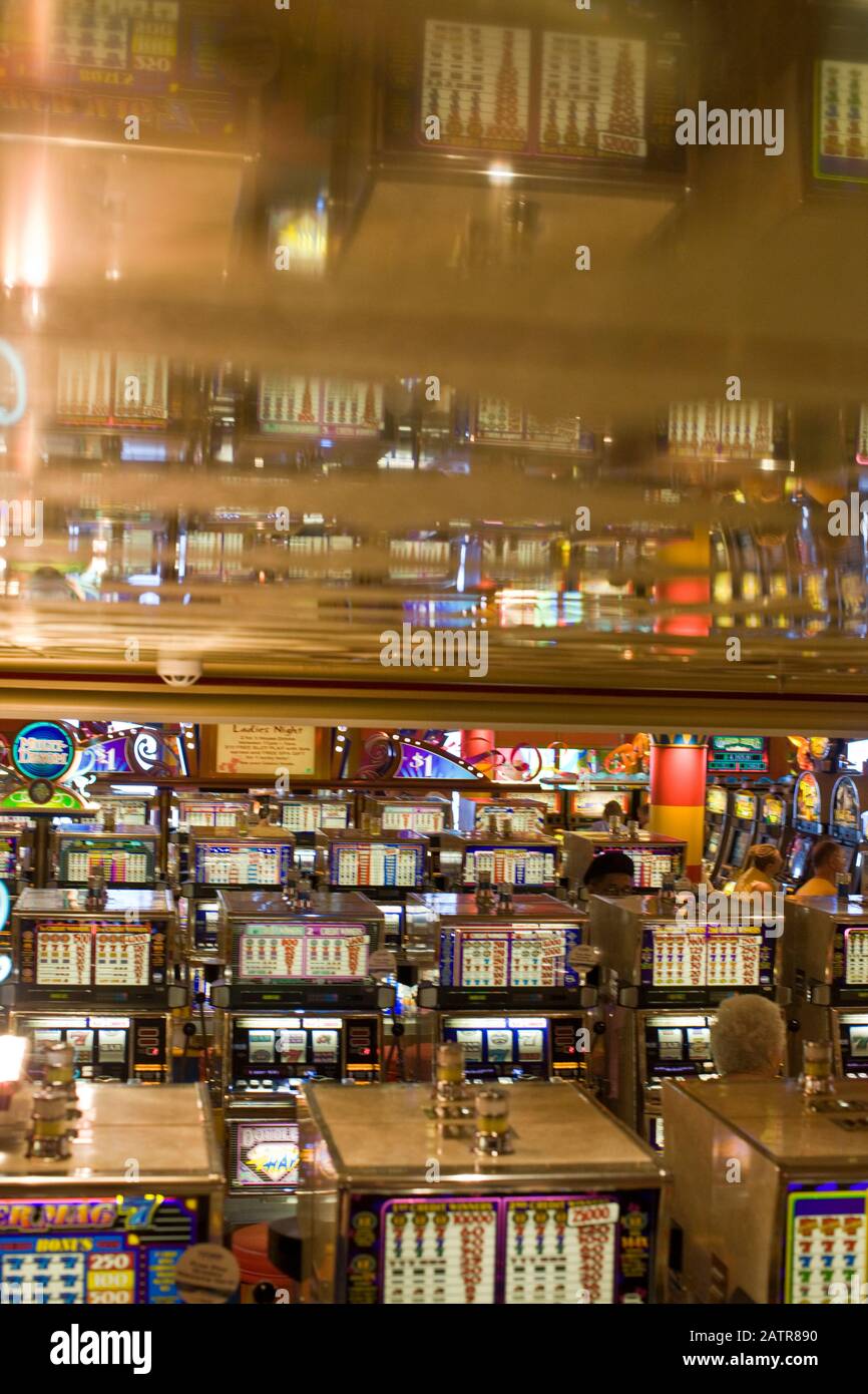 File di macchine da gioco e clienti all'interno di un casinò. Foto Stock