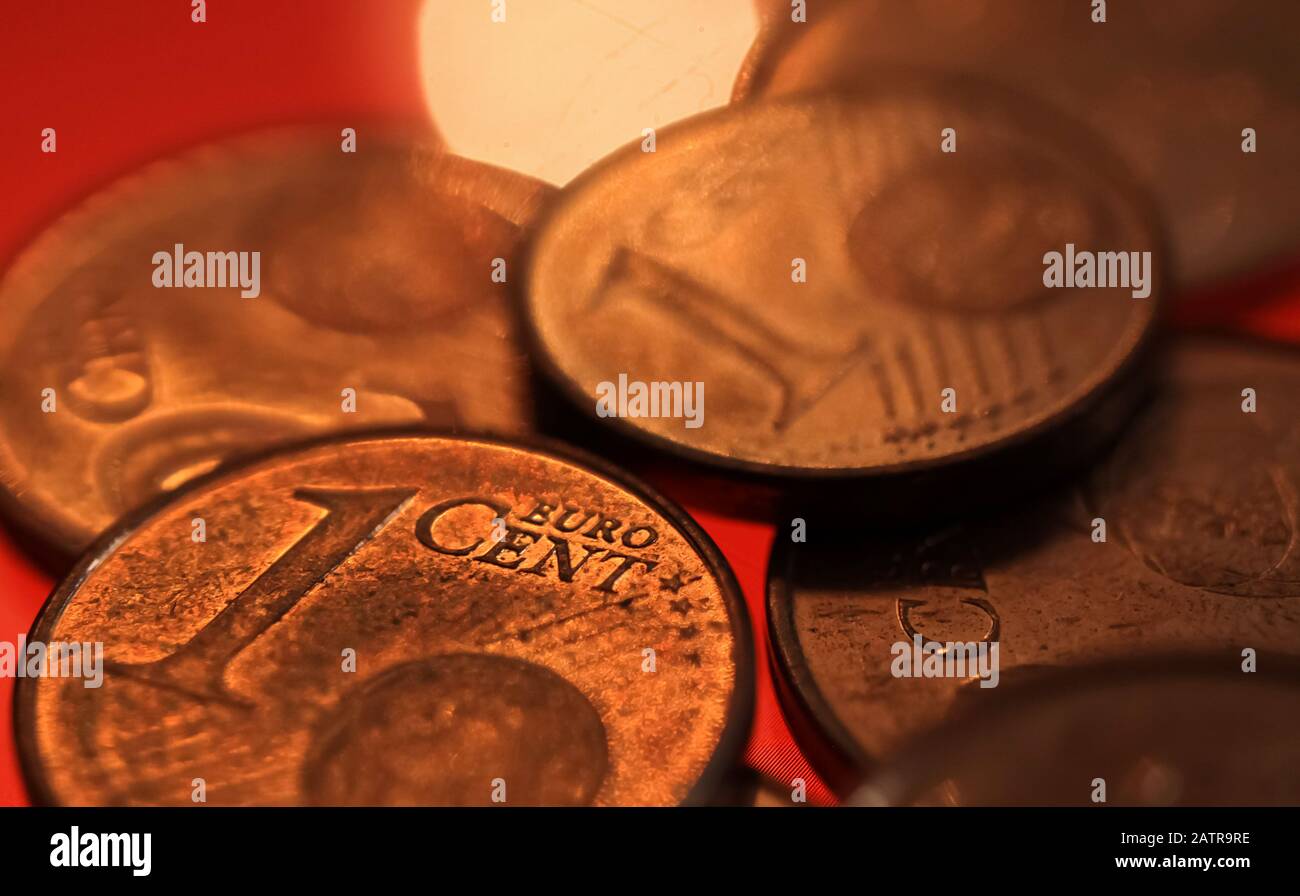 Makro primo piano di pile monete in rame da uno e due centesimi di euro su sfondo rosso lucido Foto Stock