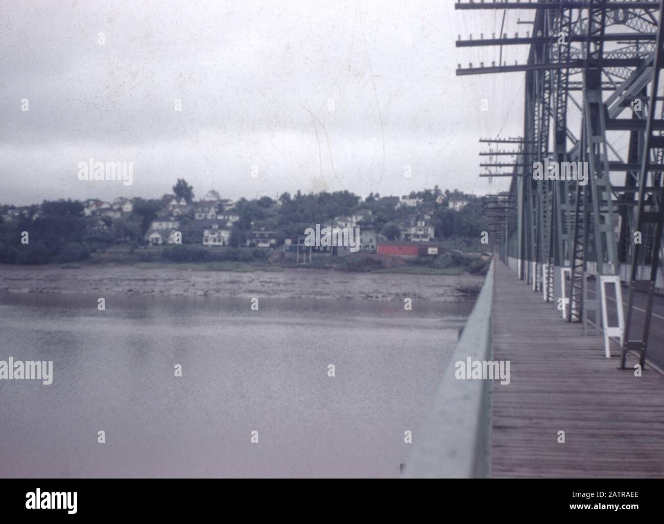 Fotografia vernacolare scattata su una pellicola analogica da 35 mm trasparente, che si ritiene dipinga un ponte di cemento grigio sopra il fiume, 1965. I principali argomenti/oggetti rilevati includono acqua, cielo, fiume, ponte, città e colore grigio. () Foto Stock