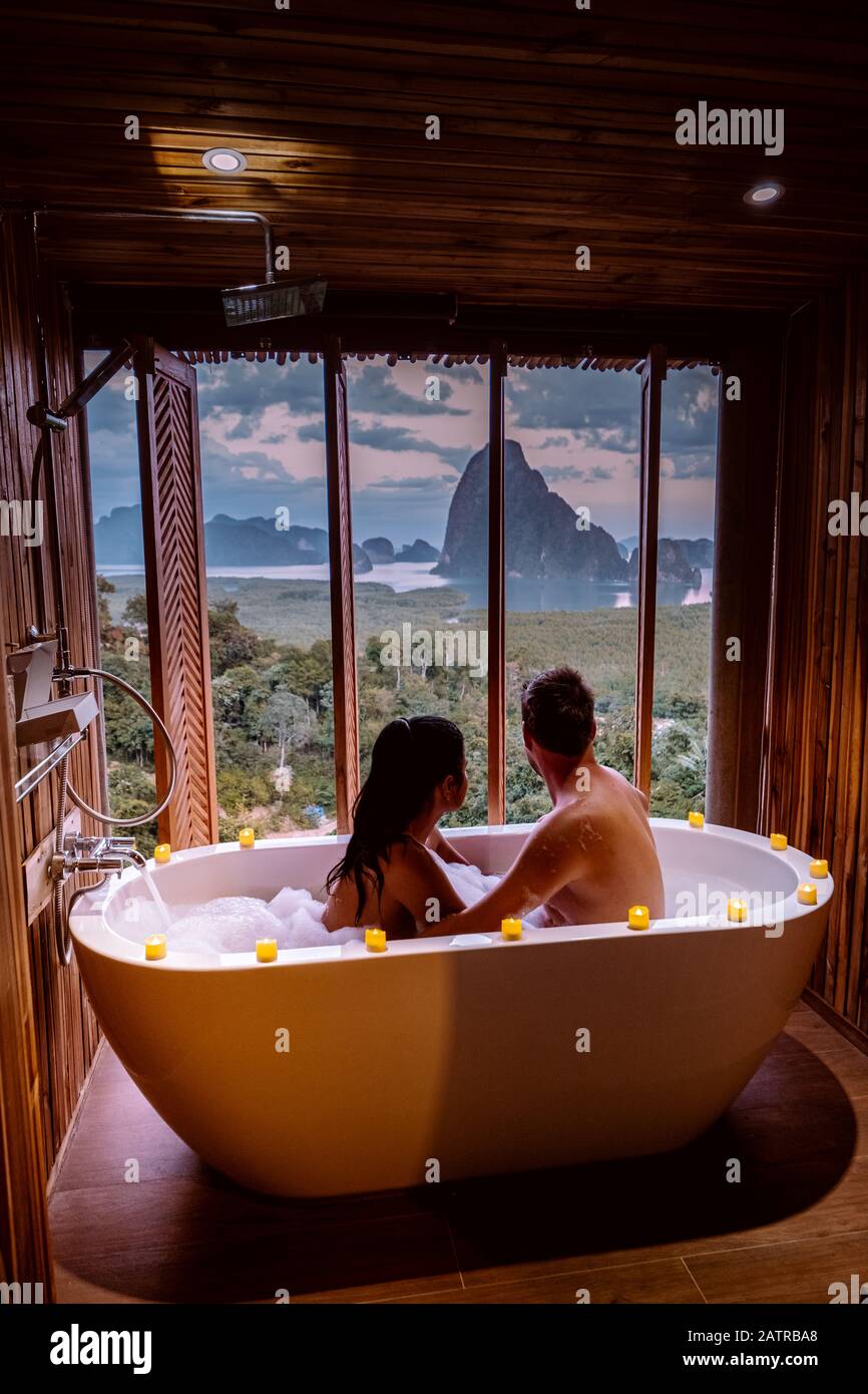 Coppia in luna di miele, vasca da bagno con vista sulla baia di Phangnga baia, bagno di lusso in legno al tramonto Thailandia Asia Foto Stock
