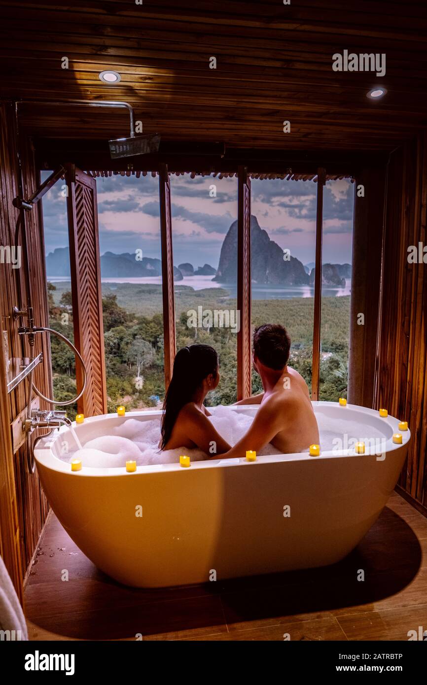Coppia in luna di miele, vasca da bagno con vista sulla baia di Phangnga baia, bagno di lusso in legno al tramonto Thailandia Asia Foto Stock