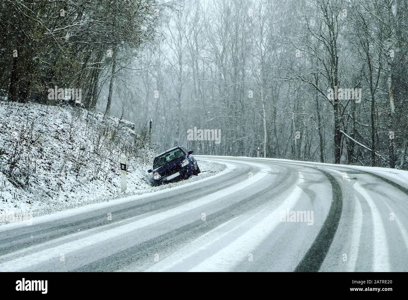 Auto abbandonata nel fosso dopo l'incidente stradale. Simboleggia le condizioni pericolose in inverno con ghiaccio, neve e neve. Foto Stock