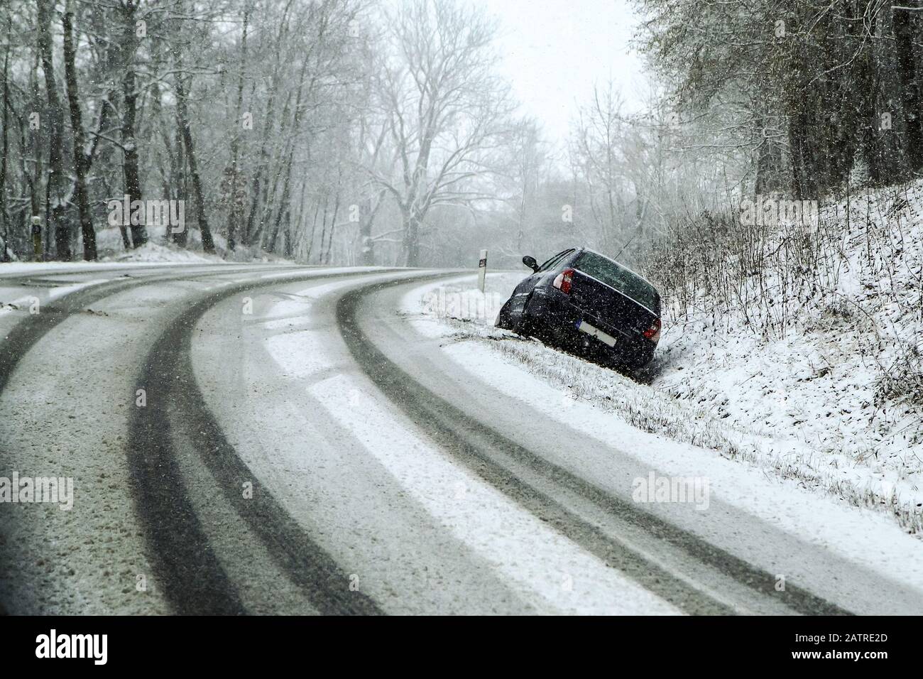 Auto abbandonata nel fosso dopo l'incidente stradale. Simboleggia le condizioni pericolose in inverno con ghiaccio, neve e neve. Foto Stock