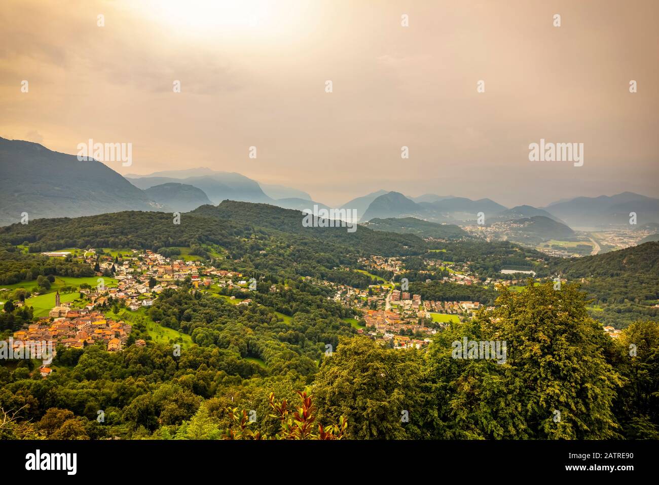 La luce del sole che si illumina attraverso il cielo sovrastato sulle dolci colline di Lugano; Lugano, Ticino, Svizzera Foto Stock