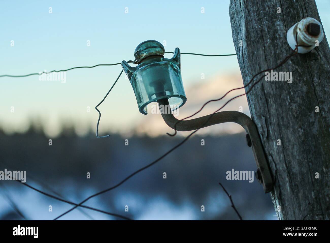 Il dettaglio del vecchio isolatore elettrico in vetro su un palo in legno. Foto Stock