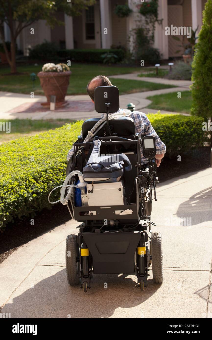 Quadriplegico in una sedia a rotelle all'esterno di una casa Foto Stock