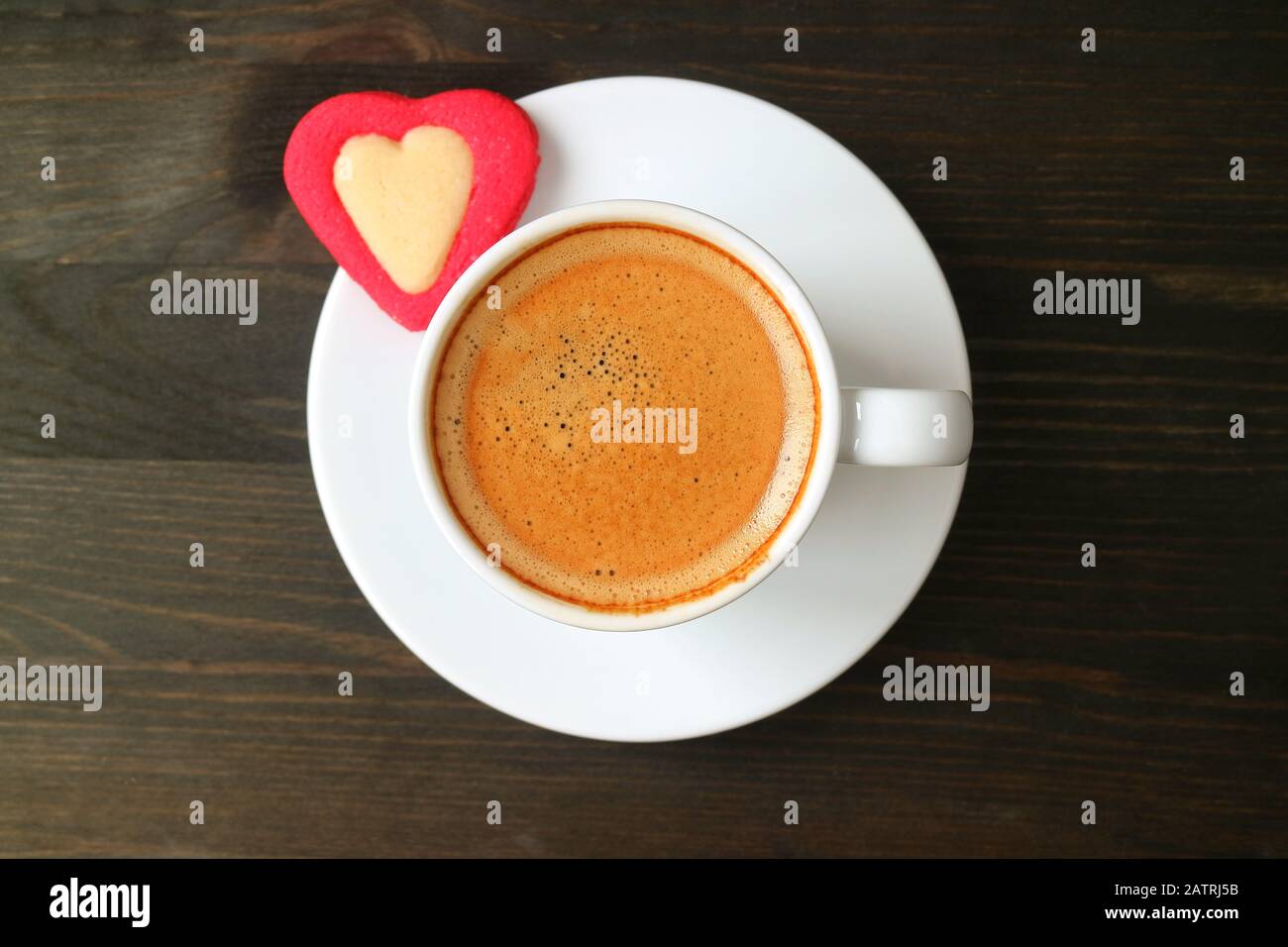 Vista dall'alto di una tazza di caffè espresso con biscotti rossi A Forma Di Cuore su un tavolo in legno marrone scuro per San Valentino Foto Stock