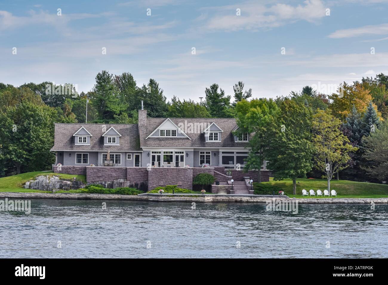 Costruzione in un'area erbosa sulla costa di un lago durante il giorno, e circondata da alberi. Concetto di stato reale. Migliaia Di Isole. Ontario, Canada. Foto Stock