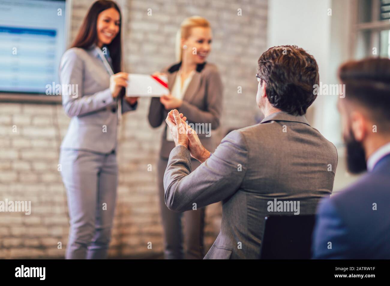 Vista frontale della donna che riceve il premio da businesswoman di fronte ai professionisti di affari applauding al seminario di affari nell'edificio dell'ufficio Foto Stock