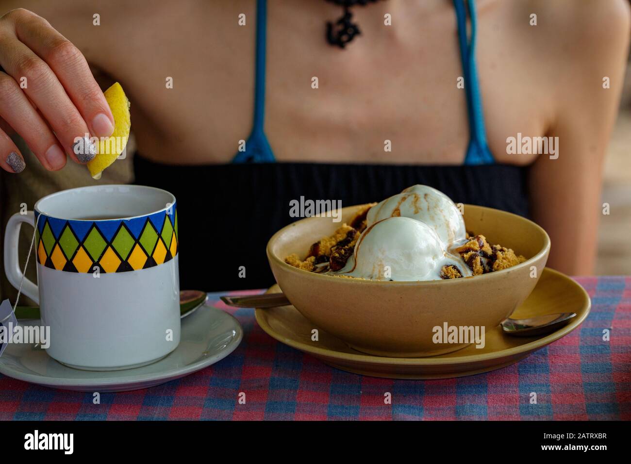 Ragazza a colazione. Una tazza di tè con gelato al limone e al cioccolato. Primo piano Foto Stock