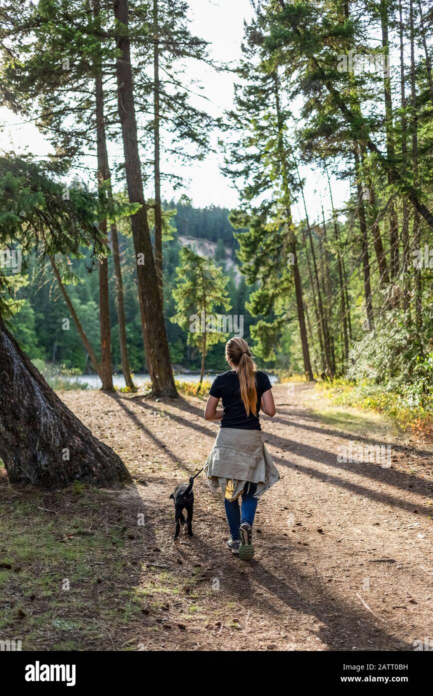 Ragazza che cammina il suo cane in un parco; British Columbia, Canada Foto Stock