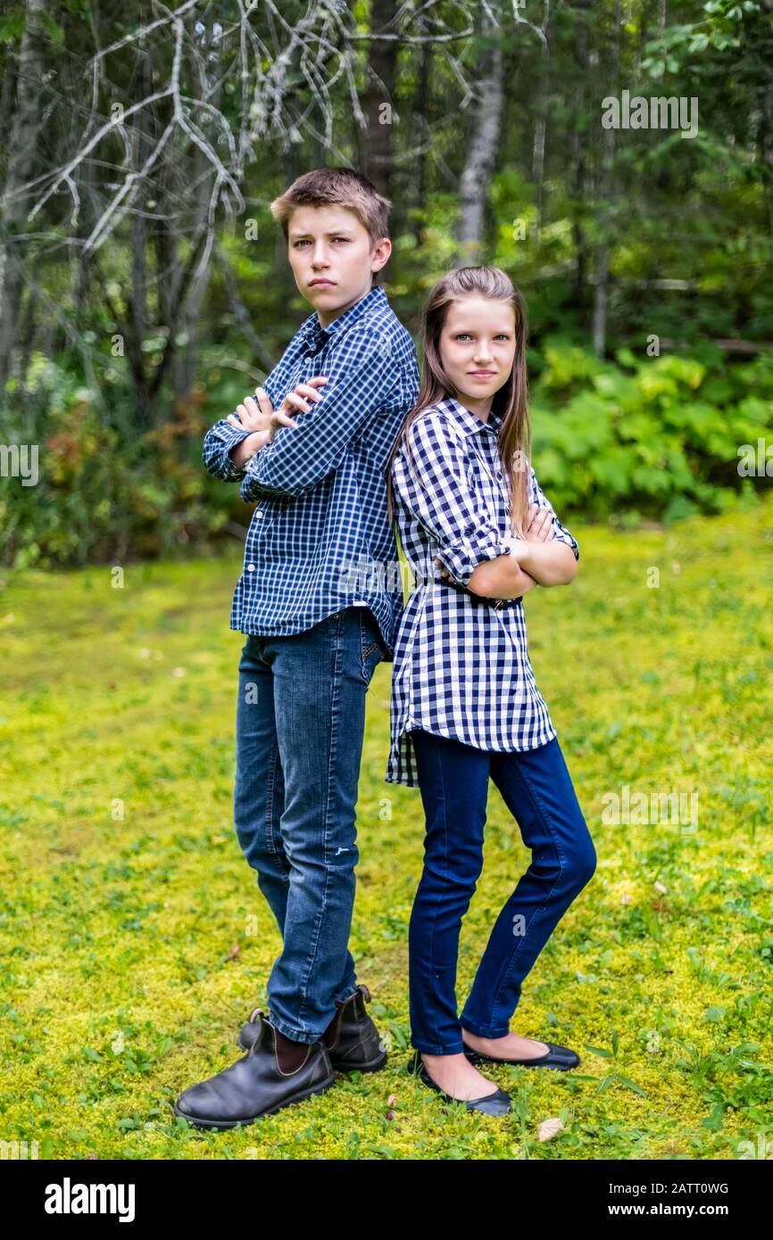 Ritratto di un fratello e di una sorella che si levano in piedi indietro con le loro braccia incrociate; British Columbia, Canada Foto Stock
