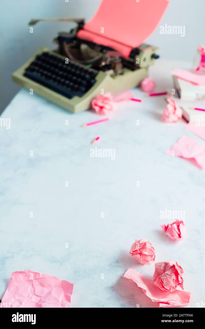 Palline di carta rosa sbriciolate e una macchina da scrivere su un luogo di lavoro scrittore. Occupazione creativa femminile. Foto Stock
