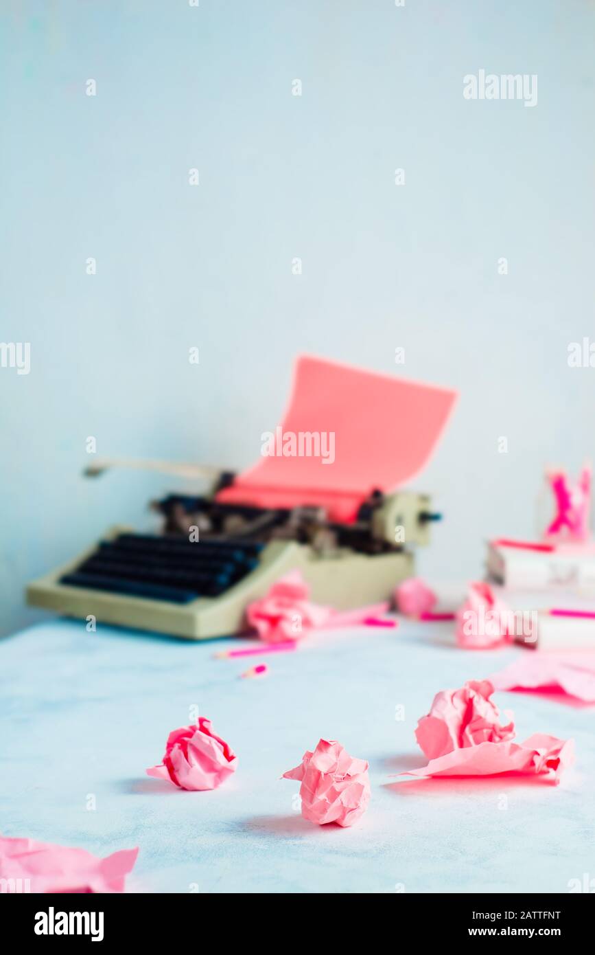 Palline di carta rosa sbriciolate e una macchina da scrivere su un luogo di lavoro scrittore. Occupazione creativa femminile. Foto Stock