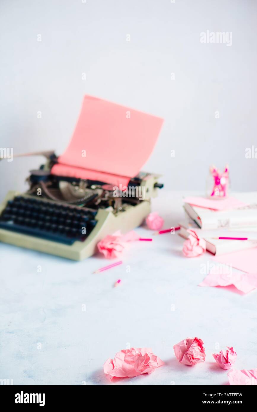 Palline di carta rosa sbriciolate e una macchina da scrivere su un luogo di lavoro scrittore. Occupazione creativa femminile. Foto Stock