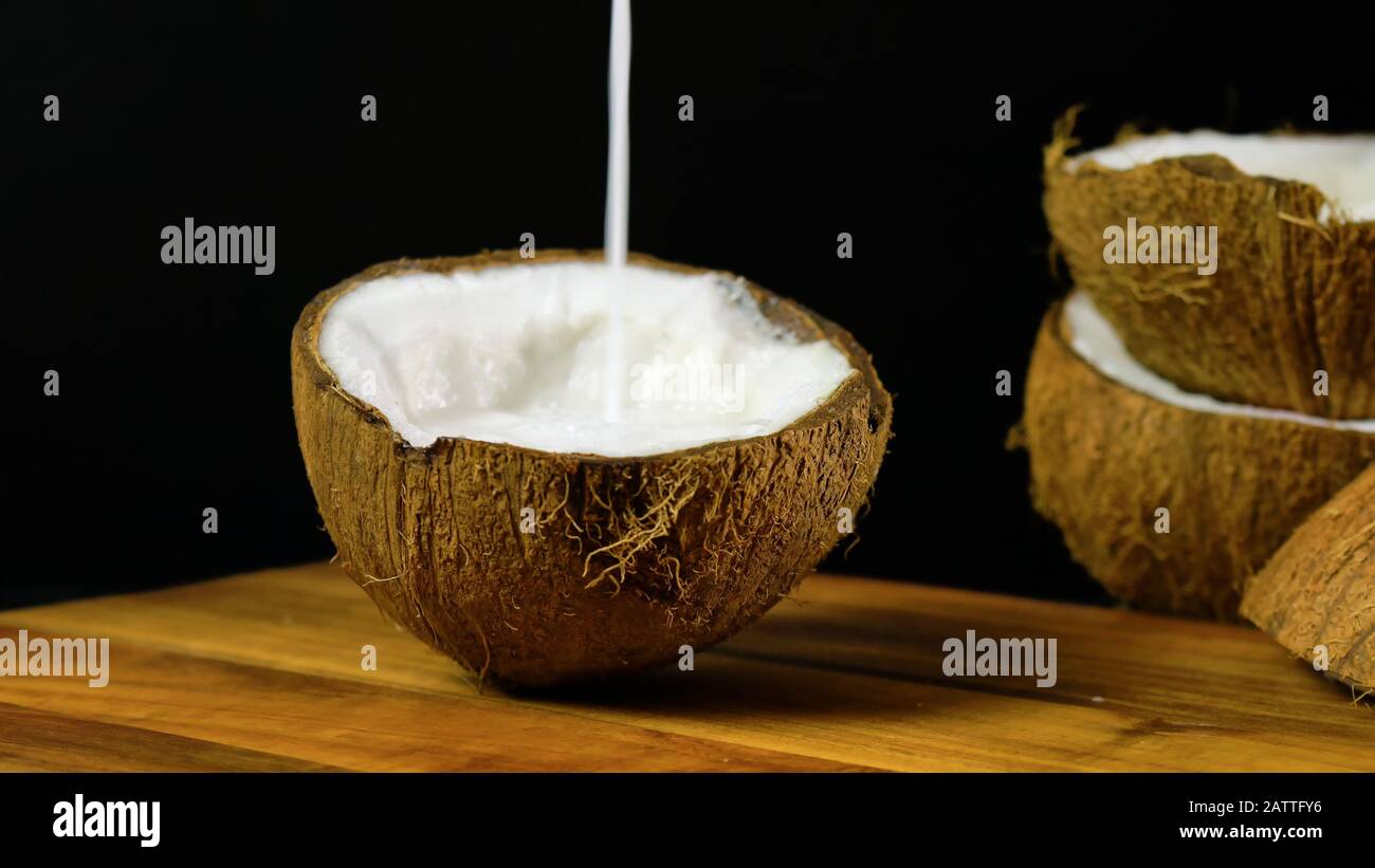 Cocco sano nutriente naturale con una vasta gamma di vantaggi dietetici e cosmetici e usi, mostra qui versare il latte di cocco in una mezza guscio Foto Stock