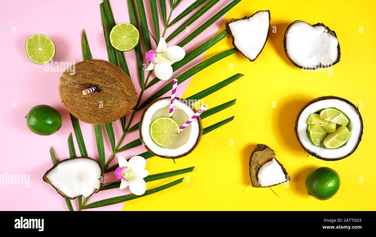 Noce di cocco estate divertente tema piatto disposizione creativa a testa con noci di cocco riempito con bevande estive e cocktail su rosa moderno e yello Foto Stock