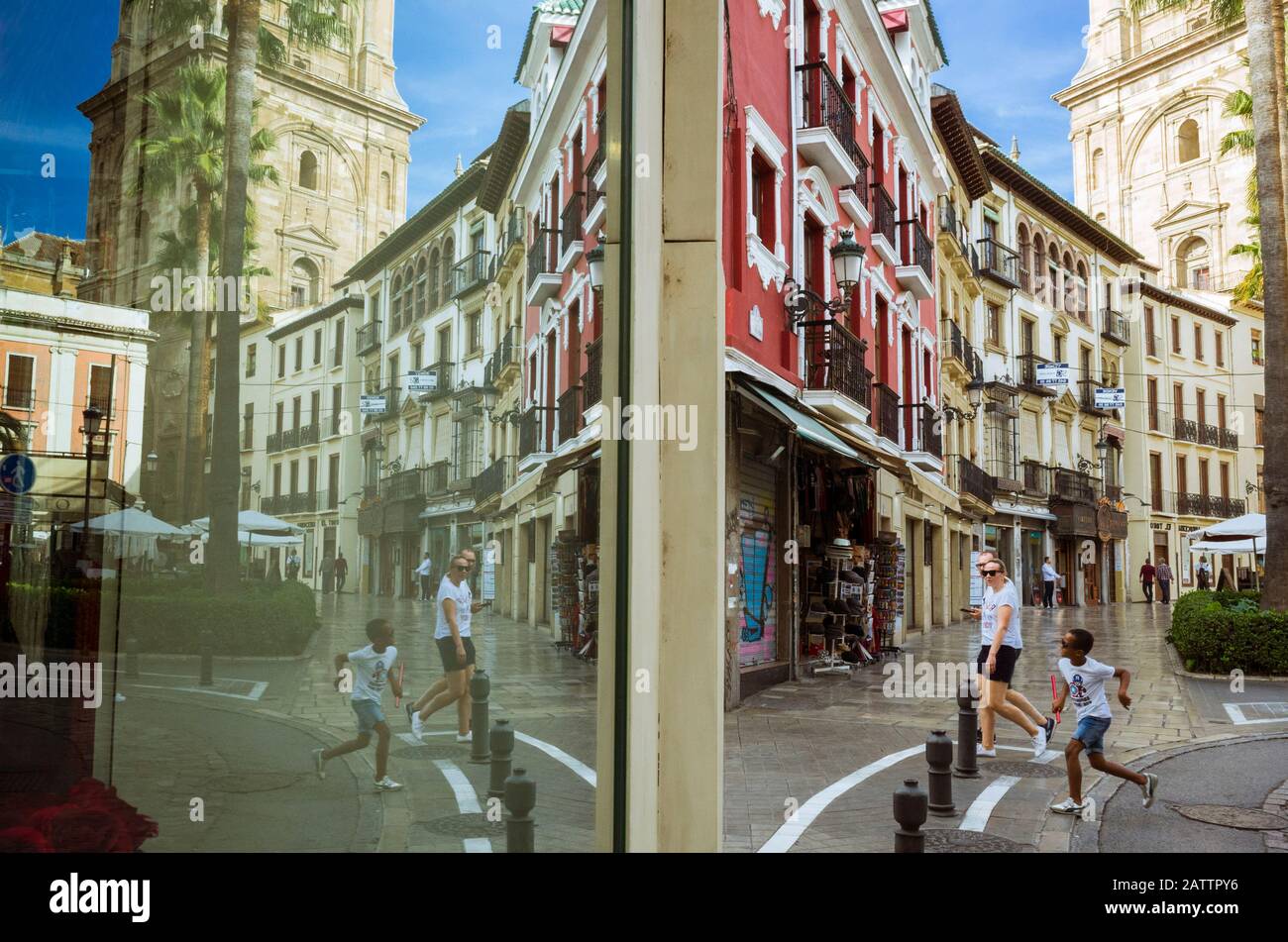 Granada, Andalusia, Spagna - Ottobre 31st, 2019 : i turisti camminano oltre una finestra del negozio che riflette la torre della cattedrale. Foto Stock
