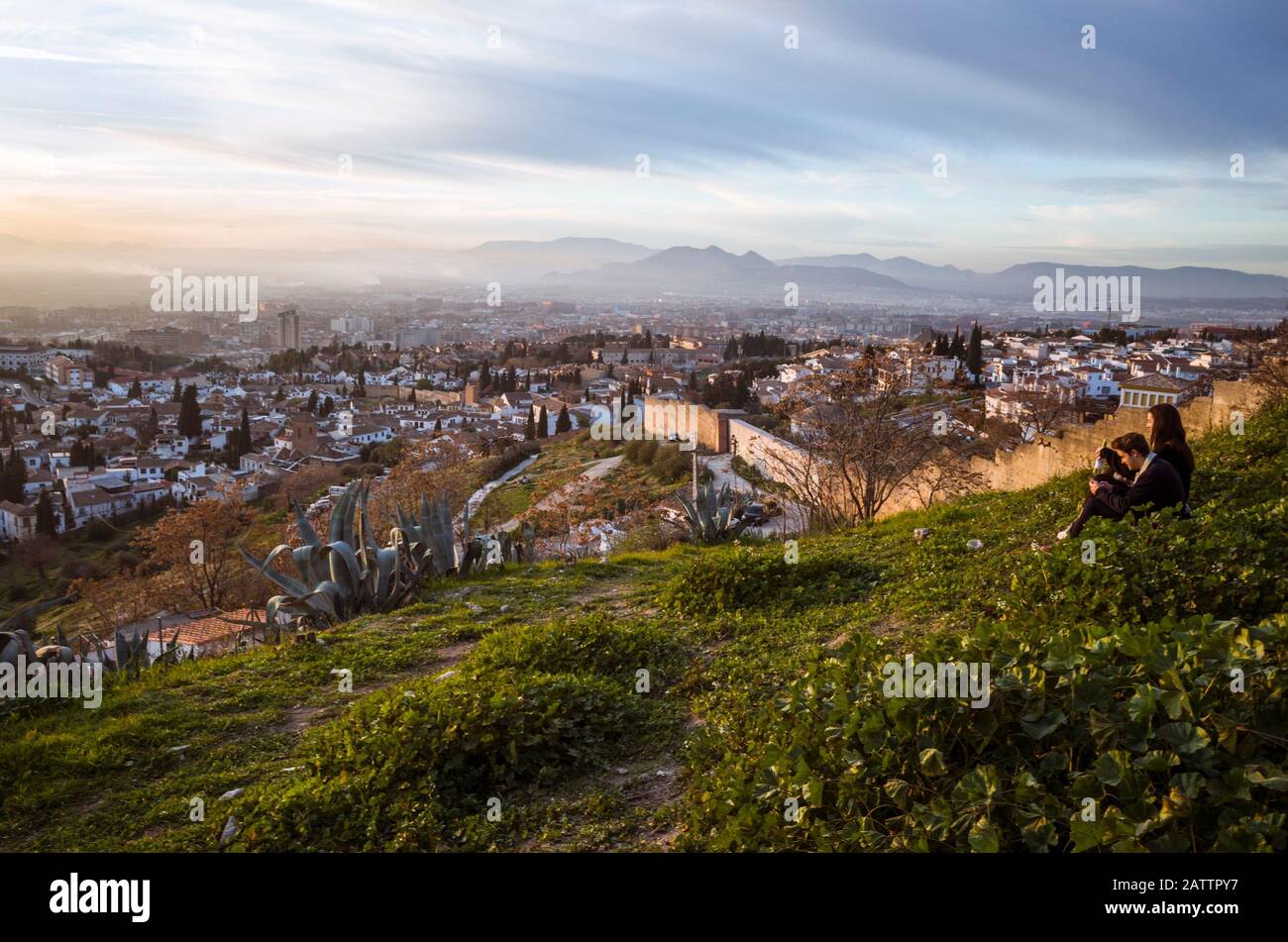 Granada, Spagna - Gennaio 17th, 2020 : una coppia guarda Granada al tramonto dalle mura della città di Albaicin al punto panoramico di San Miguel alto. Foto Stock