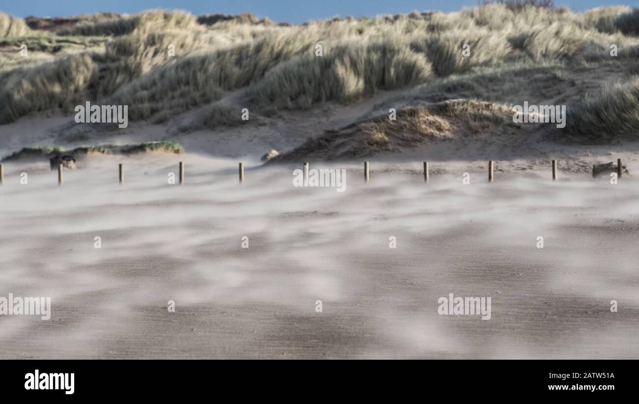 Sabbia che soffia su una spiaggia ventosa Foto Stock