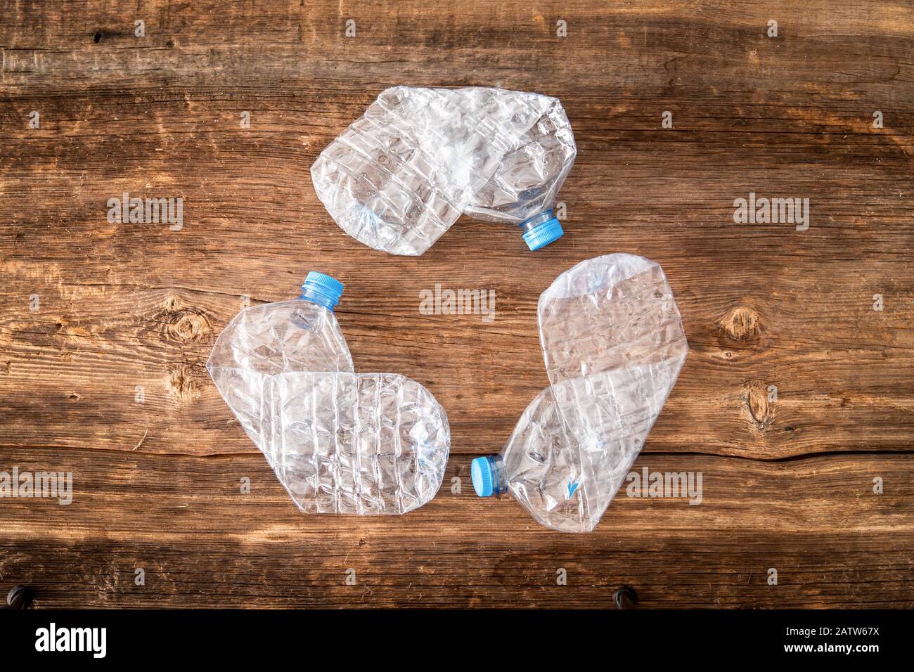 bottiglia di plastica sprecata dell'albero nella forma del simbolo di riciclaggio su fondo di legno. Foto Stock