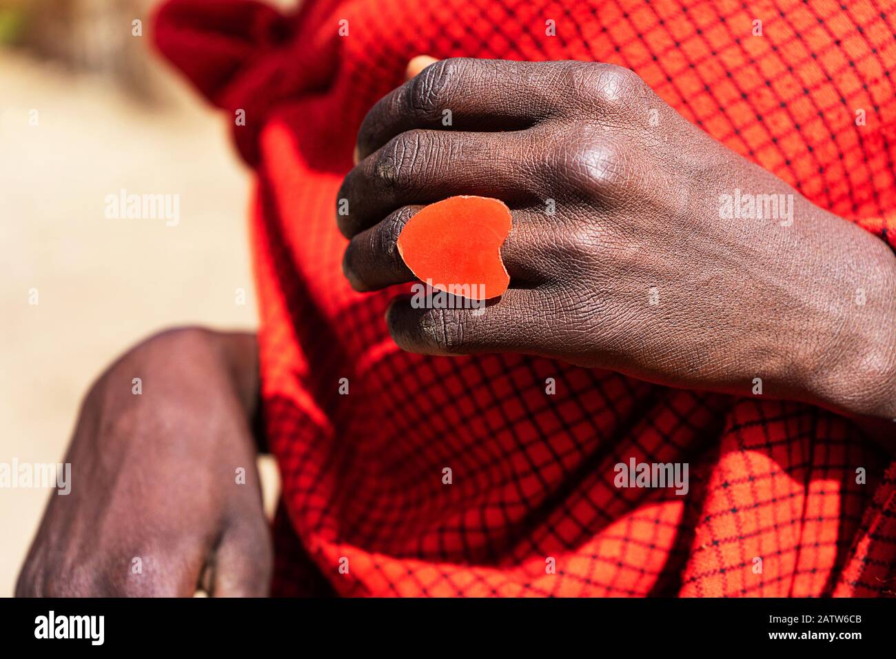 L'uomo africano che tiene una torta di smoldering nelle sue mani con un anello rosso del cuore. Tanzania, Africa. Foto Stock