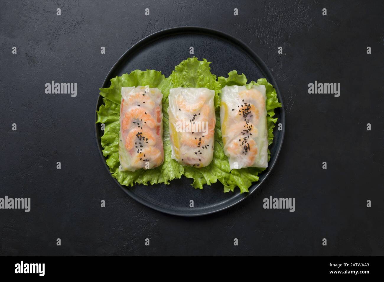 Involtini primavera vietnamiti con gamberetti al centro della tavola nera. Vista dall'alto. Cucina asiatica. Orientamento orizzontale. Foto Stock
