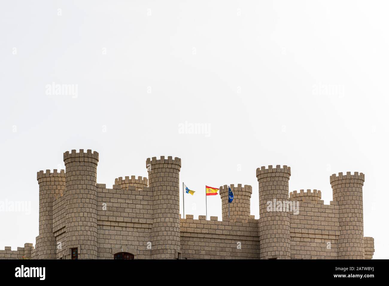 Torrette di Castello contro un cielo bianco con bandiere Canarie, spagnole ed europee battenti in Aldea Blanca, Tenerife, Isole Canarie, Spagna Foto Stock