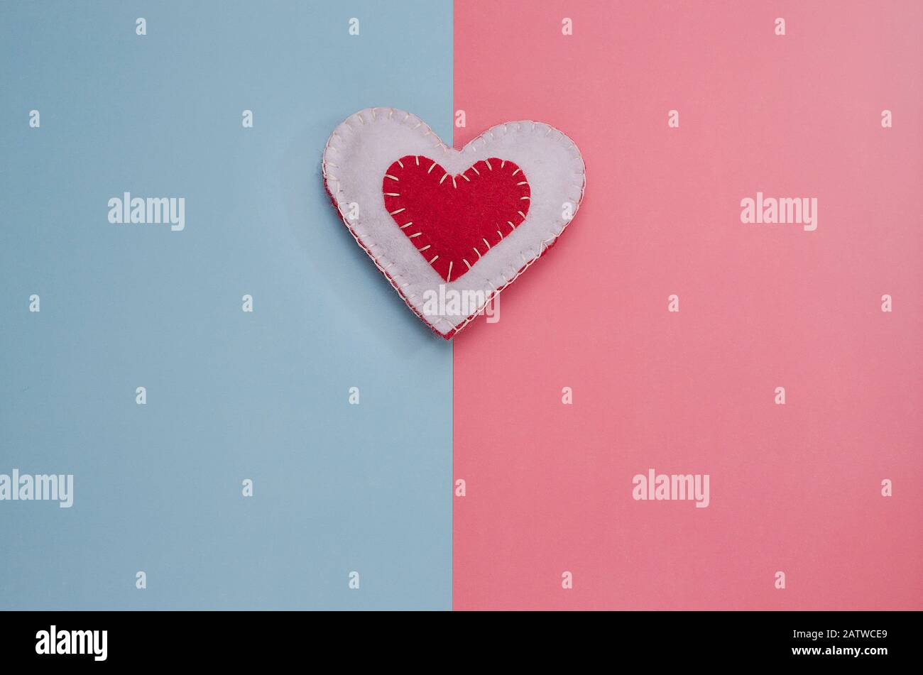 Cuore bianco e rosso fatto a mano su sfondo rosa e blu con spazio copia. Minimalismo di fondo per San Valentino, Festa della mamma, nascita di un bambino. Foto Stock