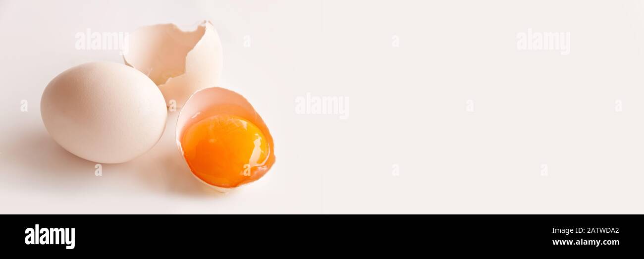 Uovo rotto e tuorlo d'uovo su sfondo panoramico bianco con spazio copia Foto Stock
