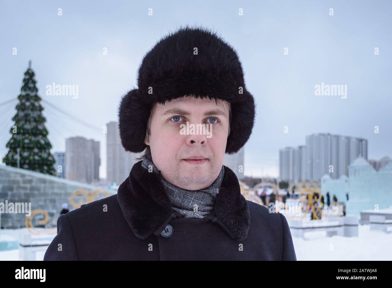 ritratto dell'uomo russo in inverno salire in giornata cupa con piazza decorata in città sullo sfondo Foto Stock