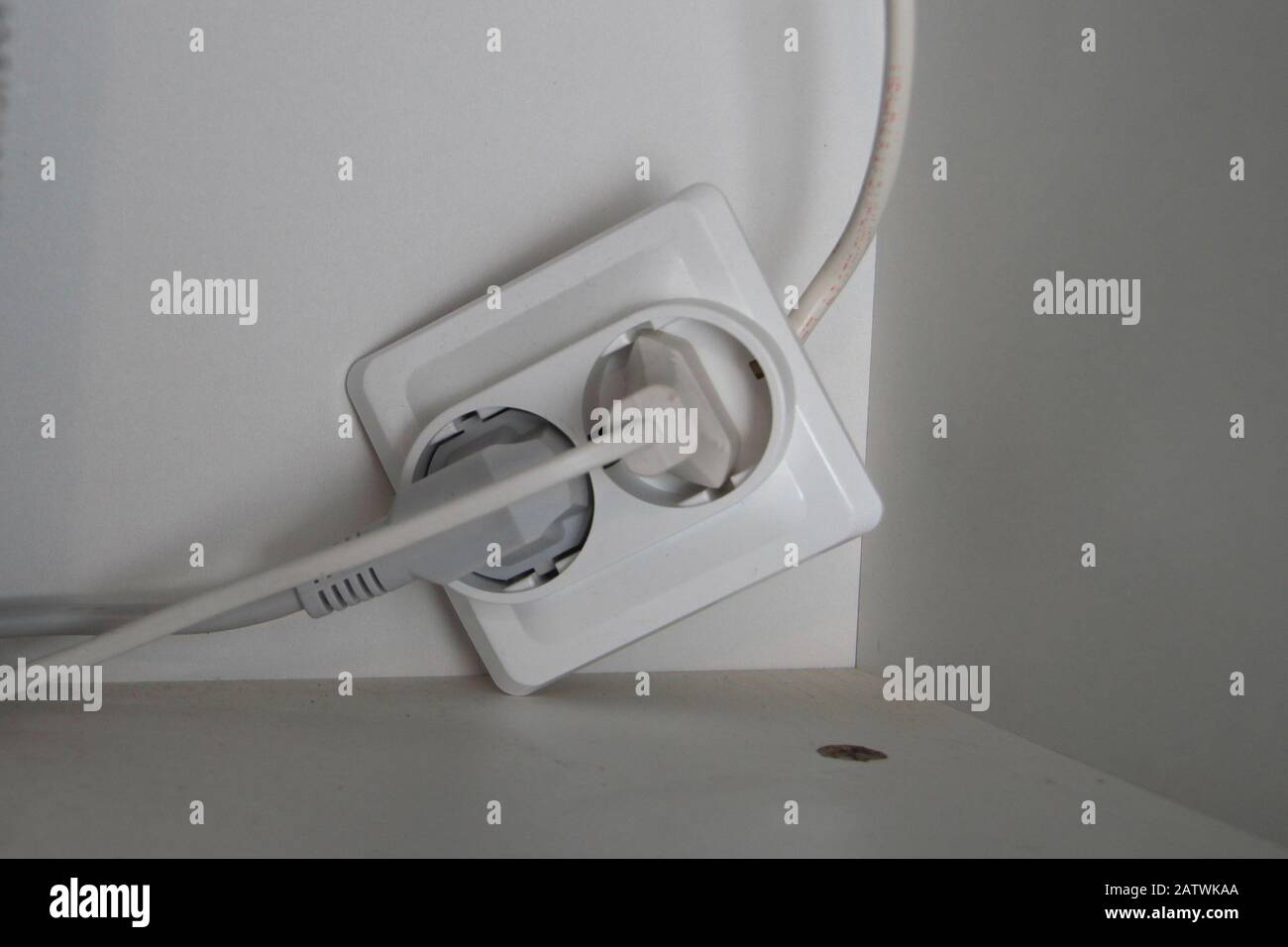 Due spine elettriche sono collegate a una presa rotta. Foto Stock