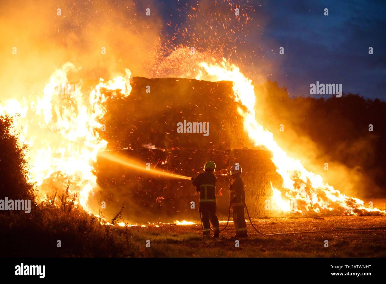Due vigili del fuoco che mettono fuori fuoco su haystack in Perry Green, Molto Hadham, Hertfordshire. REGNO UNITO Foto Stock