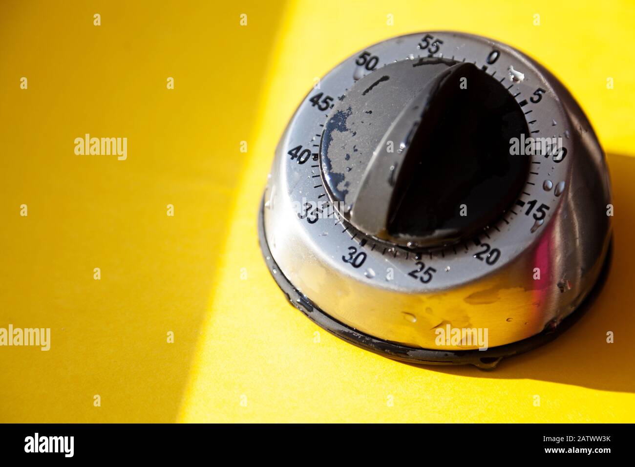 timer per uova alla luce del sole con gocce d'acqua su sfondo giallo Foto Stock