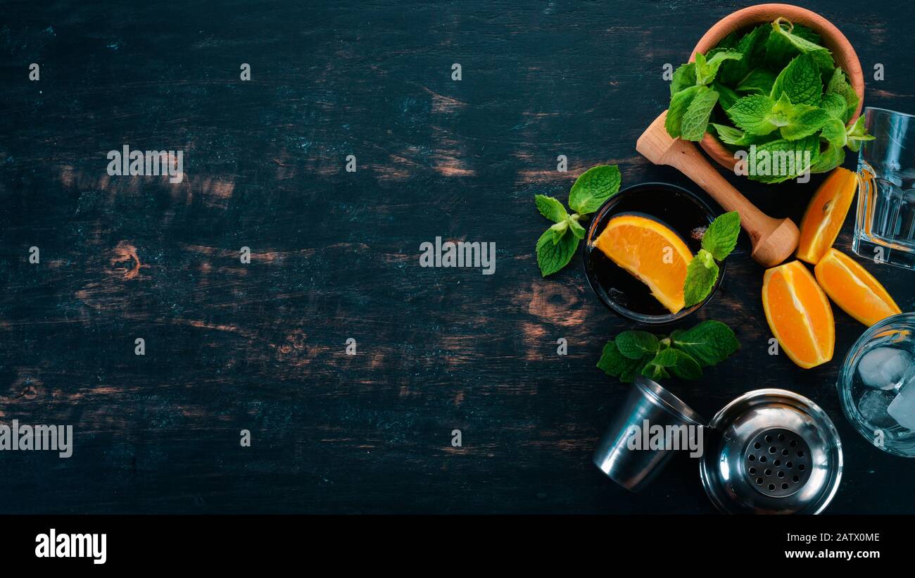 Cocktail alcolico con arancia e menta. Negroni, Long Island, Rum-Cola. Su uno sfondo di legno nero. Spazio libero per il testo. Foto Stock