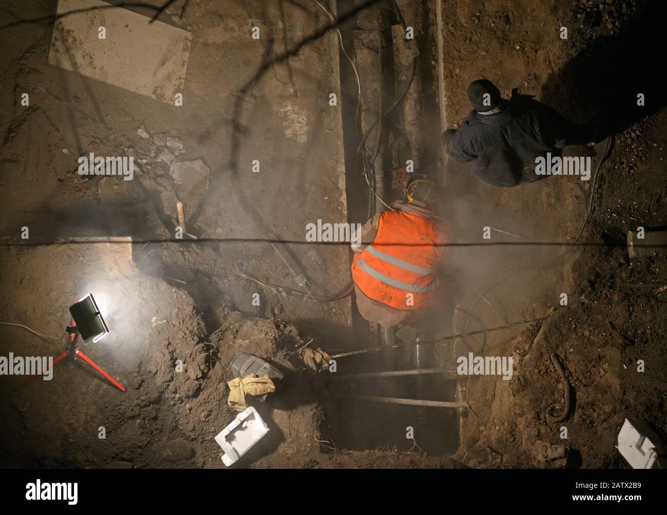 Riparazioni di emergenza. Lavoratori che saldano la rete di riscaldamento, tubazioni, usando lampada Foto Stock