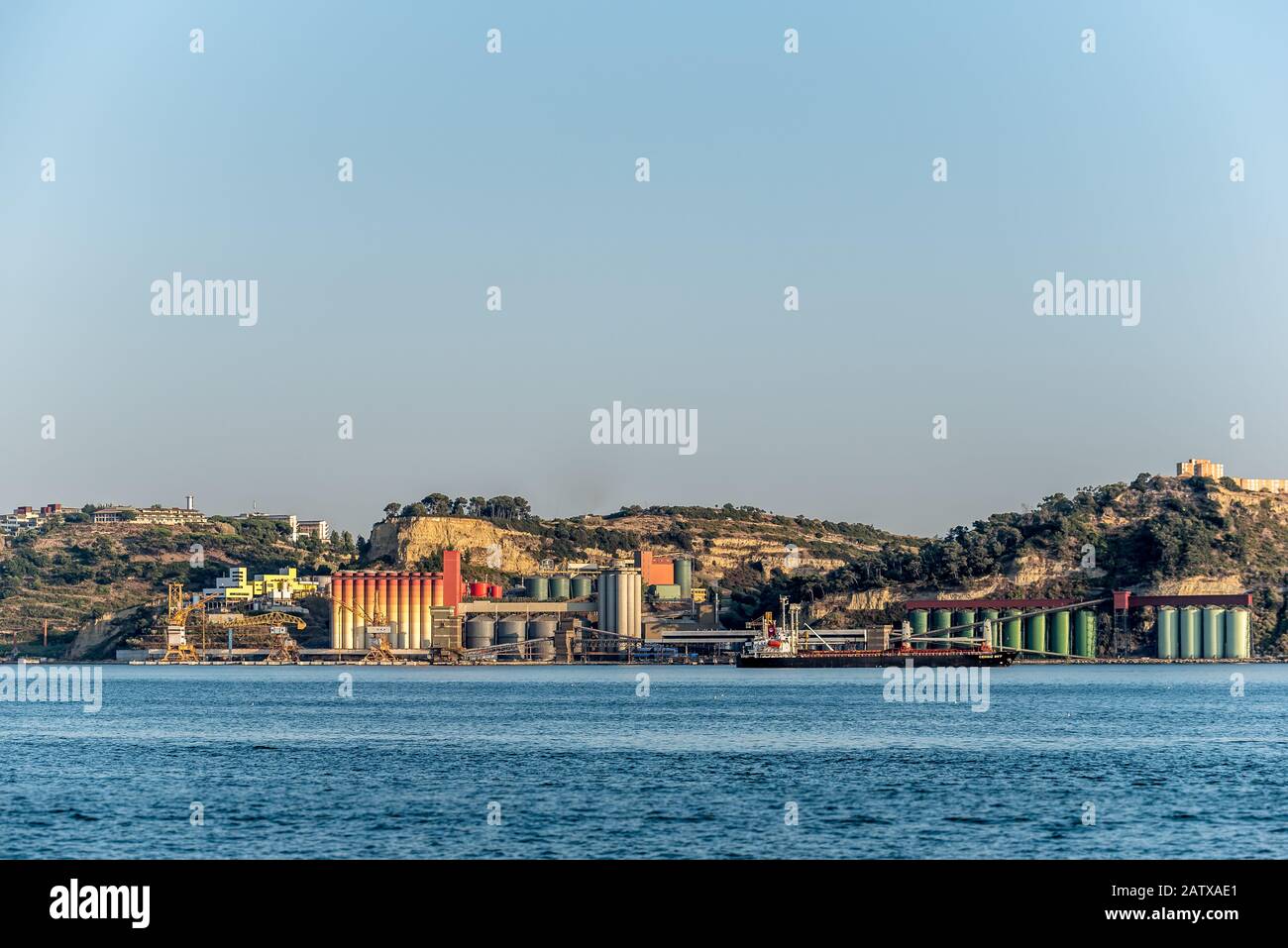 Colorati silos industriali presso il terminal di spedizione vicino alla zona urbana sul fiume Tejo in Portogallo, nel pomeriggio sole Foto Stock
